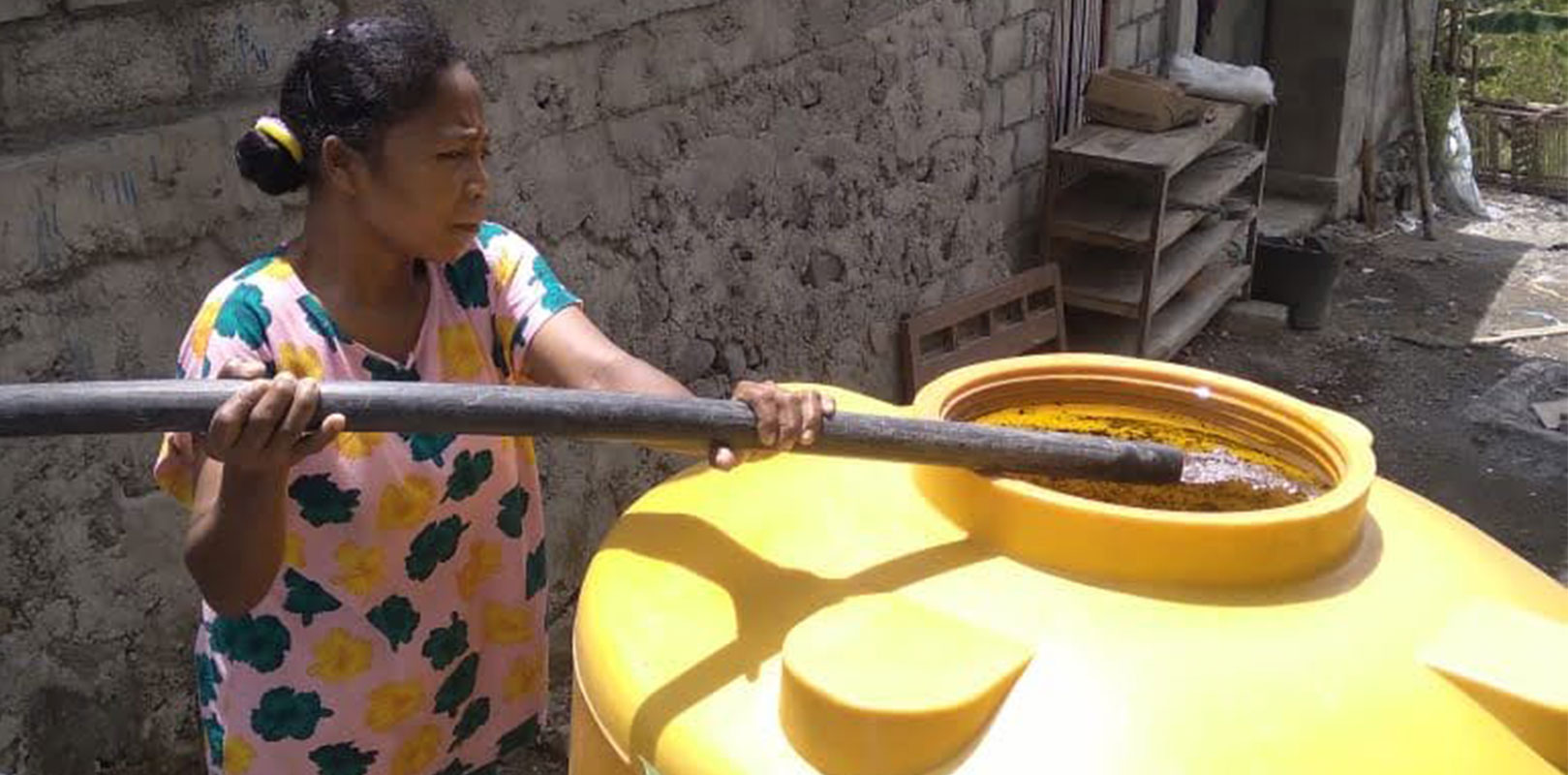 a lady collecting water in a large water tank