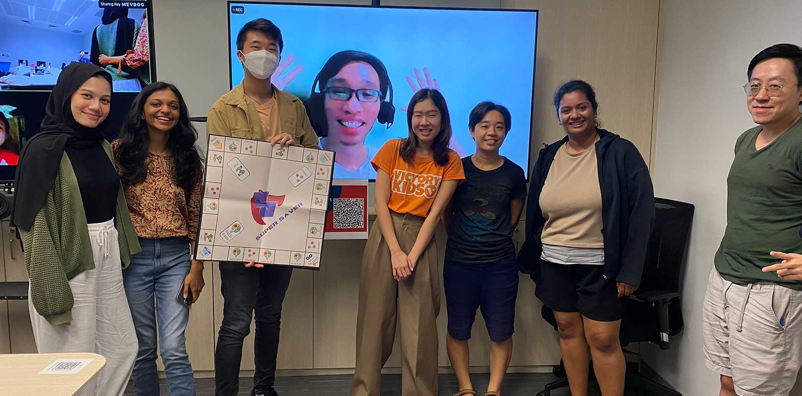 team members posing with the board game, super saver